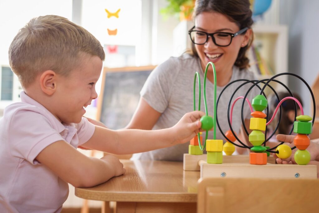 Young boy with autism playing while therapist observes