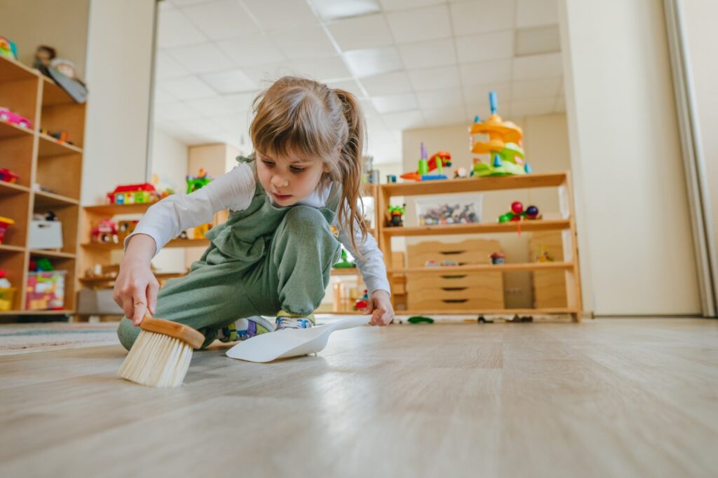 girl sweeping a floor during a natural environment training session